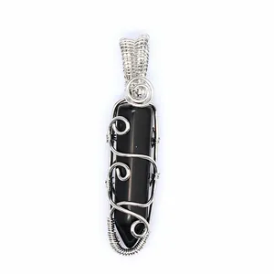 Macro detail of a black hexagonal stone pendant featuring intricate silver wire wrapping