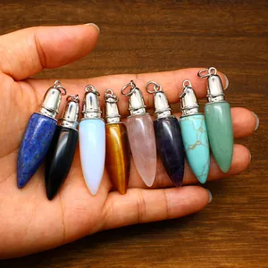 Variety of colorful bullet-shaped natural stone pendants held in hand on wooden surface