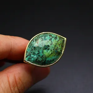 Detailed close-up of a faceted marquise-cut green gemstone ring with an elegant gold bezel setting
