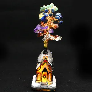 Detailed view of chakra crystal money tree with warm lighted miniature church base