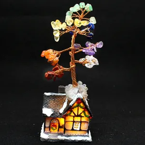 Close-up of handmade 7-chakra crystal money tree on glowing snow-covered house base