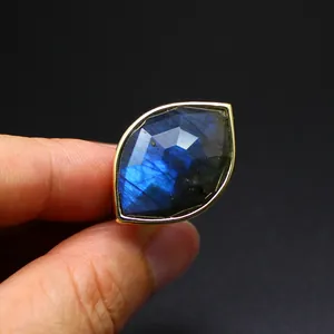 Macro view of a faceted marquise labradorite ring with a vibrant blue flash and gold band