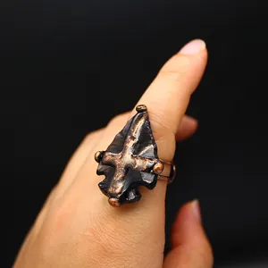 Gros plan d'une bague médiévale en obsidienne avec pointe de flèche et croix