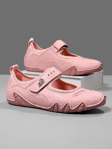 Close-up of pink Mary Jane sneakers with adjustable Velcro strap and goat logo