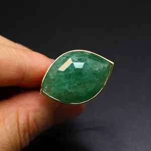Macro view of a faceted marquise-cut green crystal ring with gold-tone bezel setting