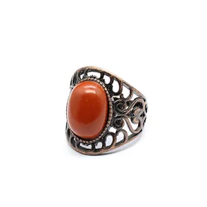 Macro detail of a vintage openwork copper ring featuring a large oval red jasper stone.