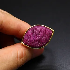 Macro detail view of a unique Eye of Horus ring featuring a textured purple gemstone set in gold