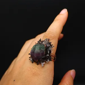 Gros plan d'une bague de style médiéval ornée d'un cristal de fluorite brut violet et vert.