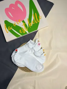 Nahaufnahme der feinen Blumen- und Kronenstickerei auf weißen Mesh-Knöchelsocken.