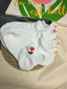 Detailansicht weißer Füßlinge aus Baumwolle mit süßen Blumenstickerei-Designs.