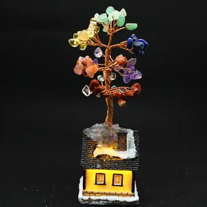 Detailed view of a handmade chakra crystal money tree on a glowing miniature snow cottage.
