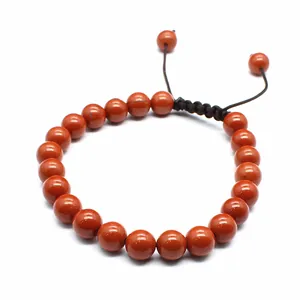 Close-up of 8mm natural red jasper stone beads on a black hand-woven adjustable bracelet.