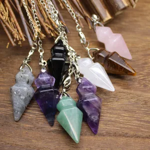 Macro detail of various natural crystal hexagonal cone pendulums on a wood surface.
