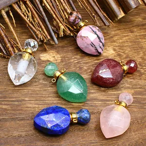 Faceted natural stone crystal perfume bottle pendants with gold-tone caps on wood
