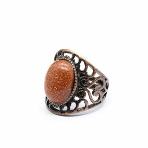 Close-up of medieval vintage hollow-out ring with oval glittery goldstone and bronze band.
