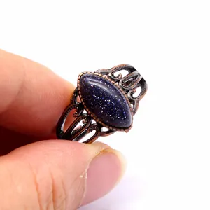 Primo piano di un anello in bronzo vintage traforato con pietra di goldstone blu marquise top.