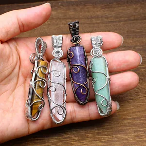 Detailed view of handmade wire wrapped natural crystal hexagonal pillar pendants in hand