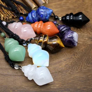 Collection of various crystal gemstone cone pendants on black cords over a wooden background