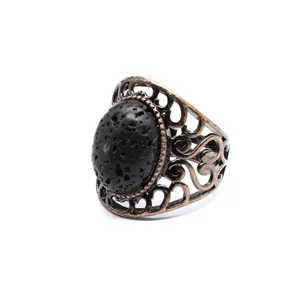 Macro detail of a vintage filigree ring with antique copper finish and black lava stone.
