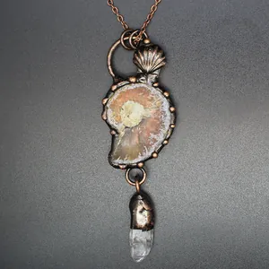 Close-up detail of a vintage medieval style ammonite fossil necklace with white crystal point