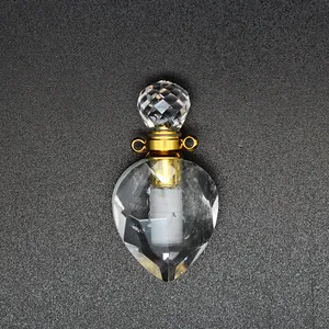 Macro detail of faceted clear crystal heart perfume bottle pendant with gold hardware.