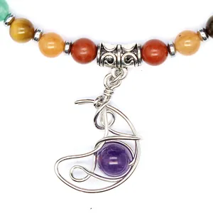 Dettaglio ravvicinato del ciondolo a luna con ametista su una collana di pietre chakra