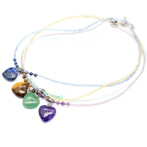 Macro view of multi-color beaded necklaces featuring heart-shaped natural stone pendants.