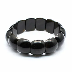 Primo piano di un braccialetto di pietra naturale nera lucida su sfondo bianco.