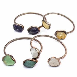 Close-up view of vintage copper open bangles with irregular raw natural gemstones
