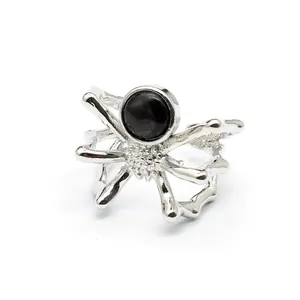 Close-up detail of a unique silver spider shaped ring set with a black natural stone