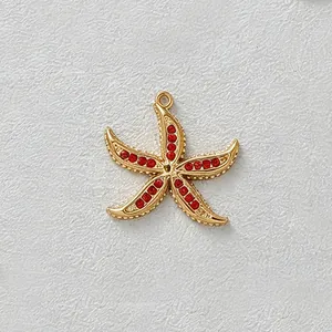 Macro view of gold-plated stainless steel starfish charm featuring vibrant red cubic zirconia inlays