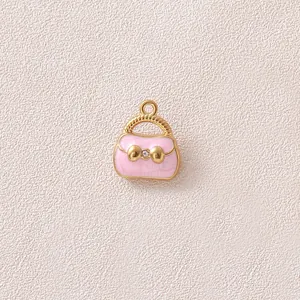Nahaufnahme eines rosa Emaille-Taschenanhängers mit vergoldeter Schleife für DIY-Schmuck.