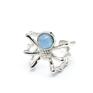 Detailed macro shot of a silver spider ring with a round light blue natural stone