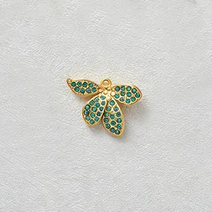 Detailed macro view of a gold-plated flower pendant with inlaid teal cubic zirconia stones