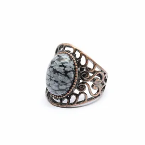 Close-up of vintage bronze filigree ring with oval snowflake obsidian stone