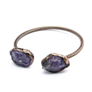Macro detail of a vintage copper open cuff bracelet featuring two raw purple amethyst stones