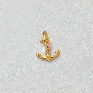 Close-up detail of a gold-plated stainless steel anchor charm with pink cubic zirconia