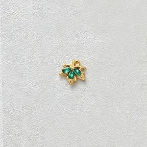 Detailed macro view of a gold-plated stainless steel leaf pendant with green zircon stones