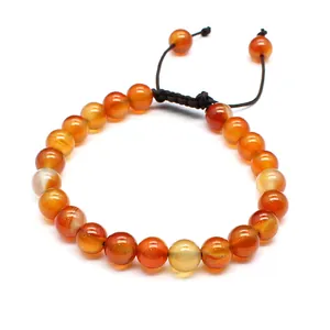 Close-up of polished 8mm orange natural stone beads on a hand-woven adjustable bracelet