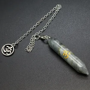 Dettaglio ciondolo a pendolo in labradorite esagonale con simbolo Om dorato e catena.