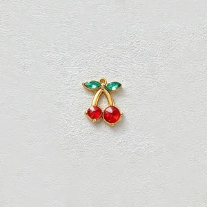 Close-up of a gold-plated stainless steel cherry pendant with red and green zircons.