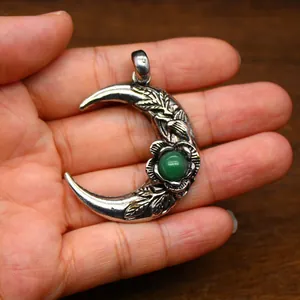 Detalle de colgante de luna plateado vintage con gema verde y grabados intrincados