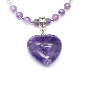 Detailed close-up view of a heart-shaped purple amethyst pendant on a beaded necklace