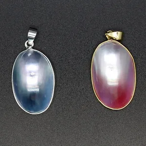 Detail shot of oval Mabe pearl pendants in silver and gold frames with iridescent luster