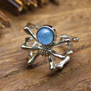 Detailed macro view of a unique silver spider ring with a round blue natural stone cabochon