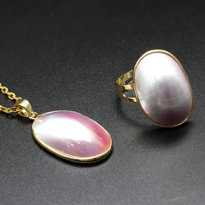 Close-up detail of pink Mabe pearl pendant and adjustable ring set in gold plating