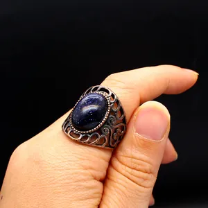 Close-up of vintage hollow ring with blue goldstone on finger
