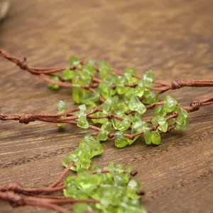 Macro detail of green peridot chips hand-woven into a rustic brown net cord detail view.