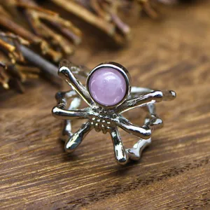 Macro detail view of a spider open ring featuring a round purple kunzite stone on wood