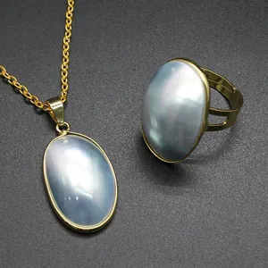 Detailed view of iridescent Mabe pearl shell pendant and matching gold ring jewelry set